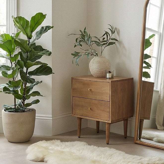 Fishe and Lilly Bedside Table in natural wood finish with two drawers and a pot plant beside it