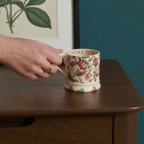 Elegant Fishe and Lilly bedside table featuring a smooth finish with a floral mug on top