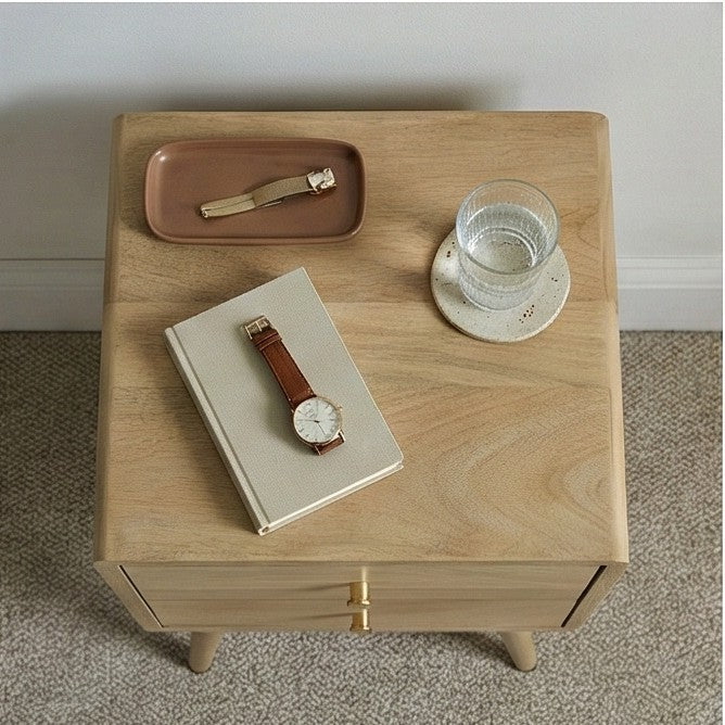Natural Wood Fishe and Lilly Bedside Table with a Watch, Notebook, and Glass of Water on Top
