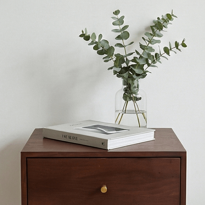 Fishe and Lilly bedside table with a book and glass vase featuring eucalyptus on top