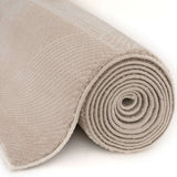 Soft beige rug rolled up, showcasing its plush texture and neutral colour for home decor