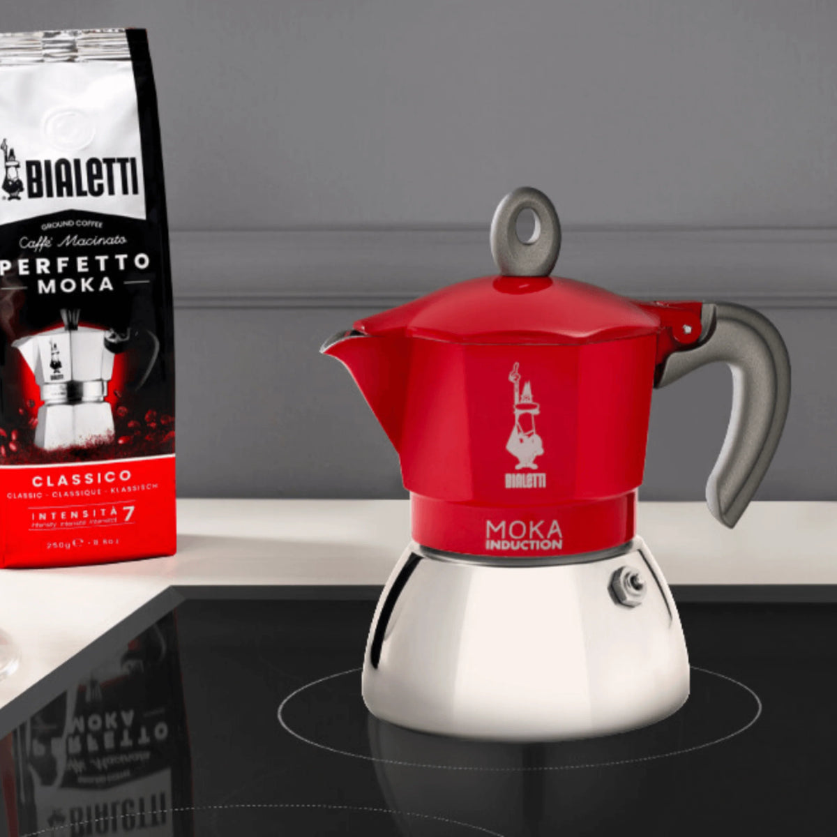 Bialetti Moka Induction Coffee Maker in red next to Bialetti coffee bag on a modern kitchen counter