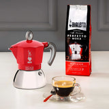 Bialetti Moka Induction Coffee Maker in red with Perfectto Moka coffee and a brewed espresso cup
