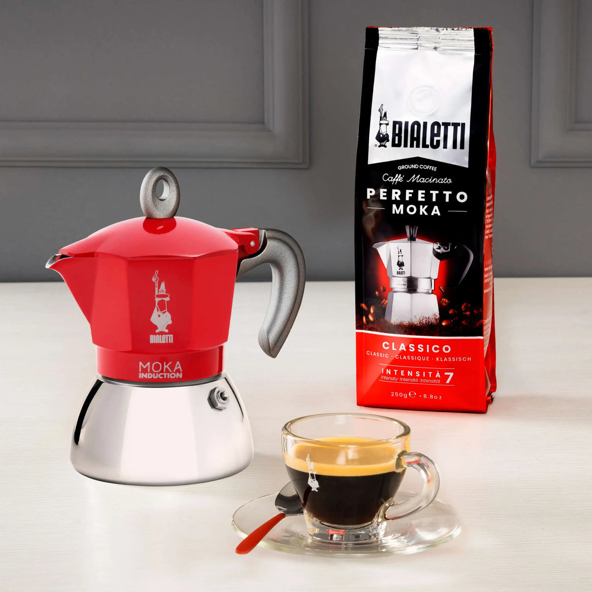 Bialetti Moka Induction Coffee Maker in red with Perfectto Moka coffee and a brewed espresso cup