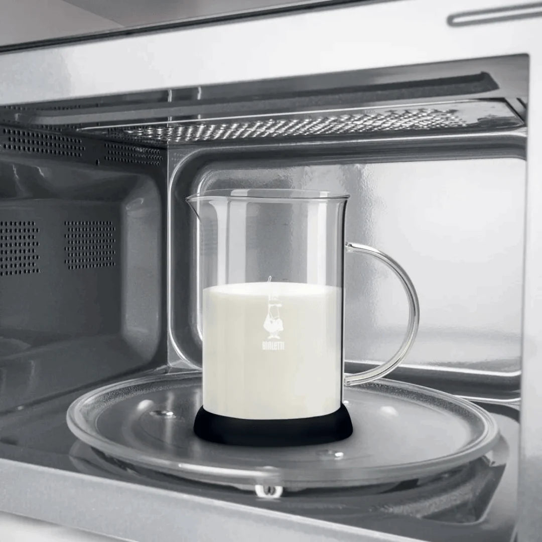Bialetti Milk Frother heating milk in microwave with clear glass pitcher and black base