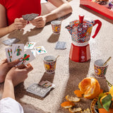 Bialetti Moka Express in vibrant design with cups and playing cards in a social setting