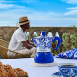 Bialetti Moka Induction Coffee Maker in Blue Floral Design on a Table with Pastries and Scenic View