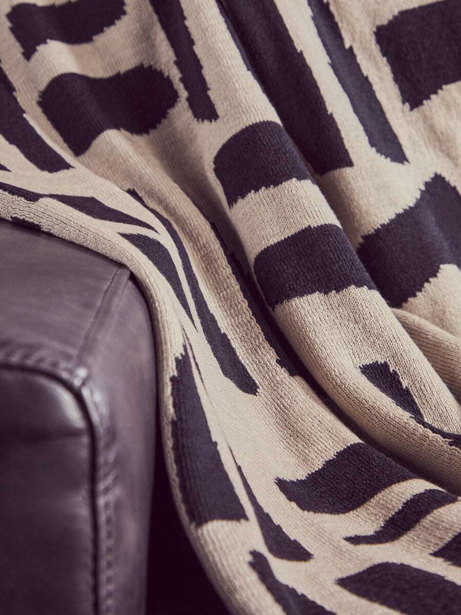 Orsina Black Throw with a stylish abstract pattern draped over a comfortable couch