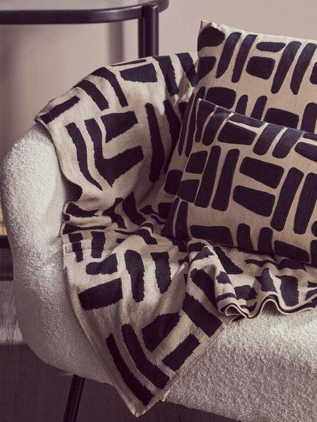 Orsina Black Throw on a cosy chair with patterned cushions for stylish home decor