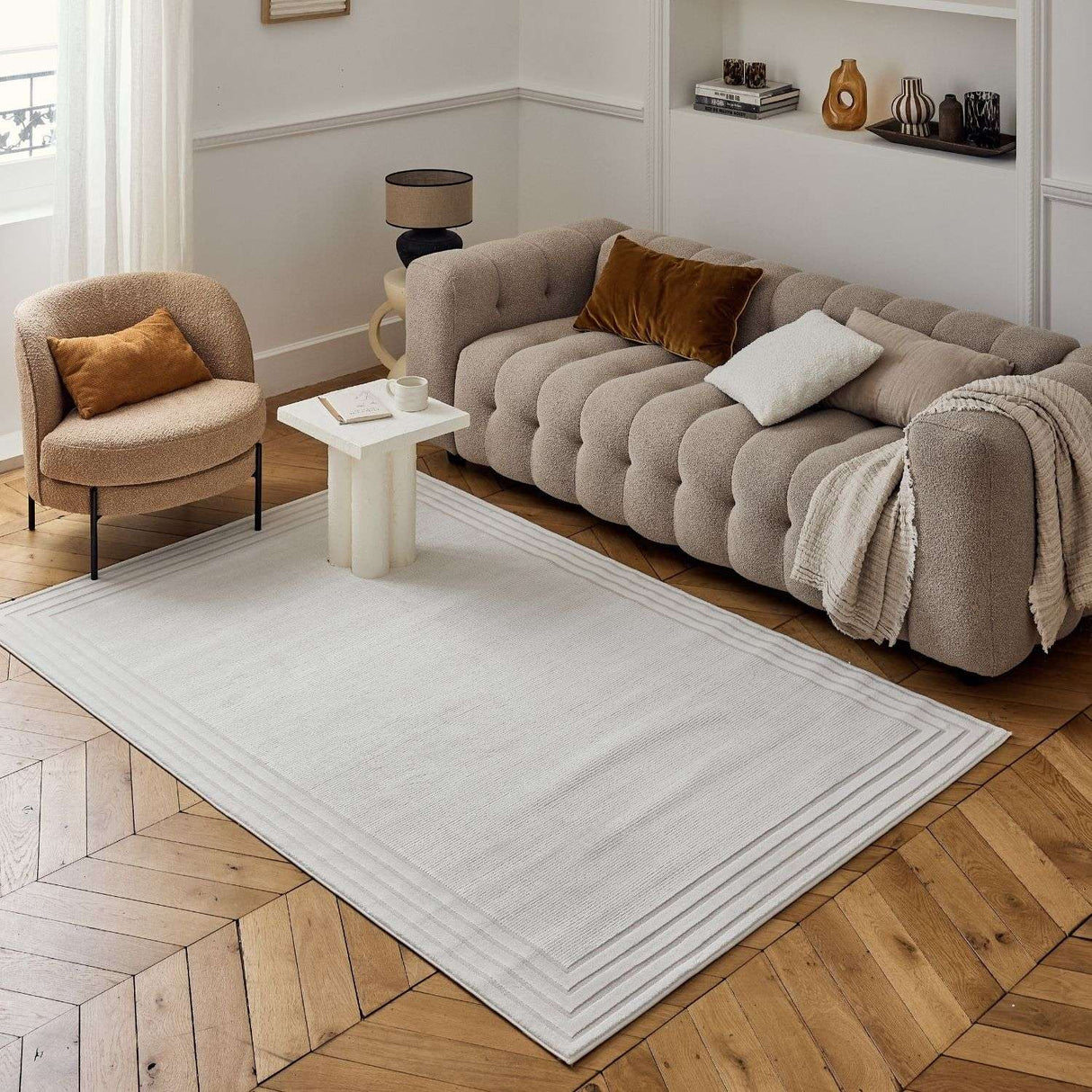 Neutral Bordered Rug displayed in a modern living room with a stylish sofa and elegant decor