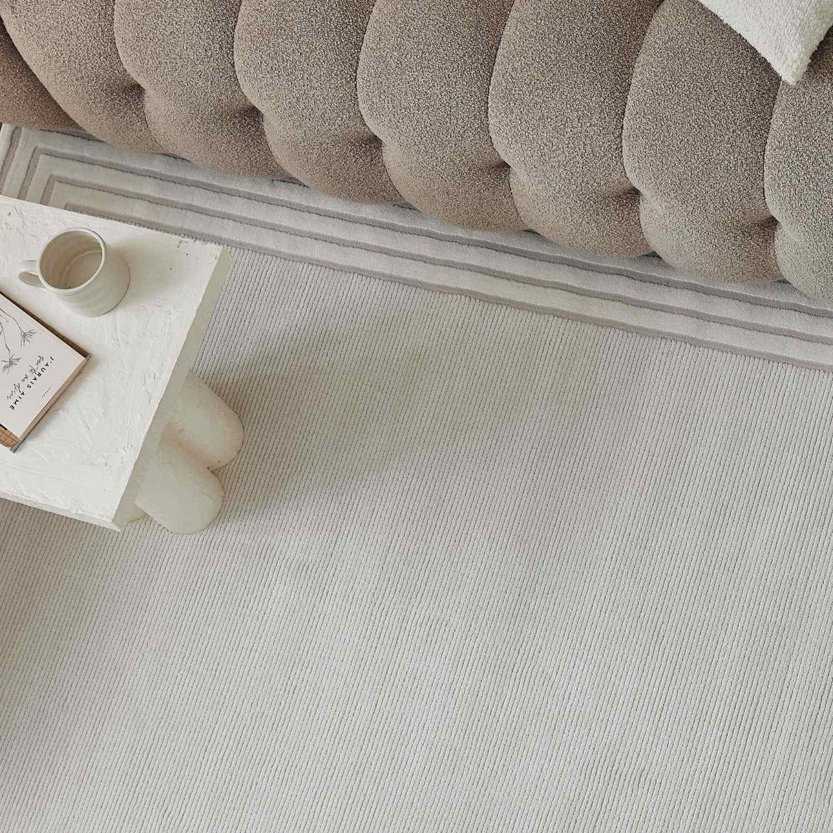 Light-coloured Bordered Rug placed under a plush sofa, enhancing modern home decor