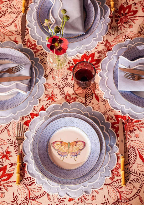 Casa by Josephine Jenno tablecloth featuring a vibrant red floral design with matching plates and cutlery