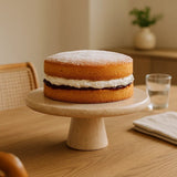 Orsina Cake Stand showcasing a sponge cake with cream and jam on a wooden table