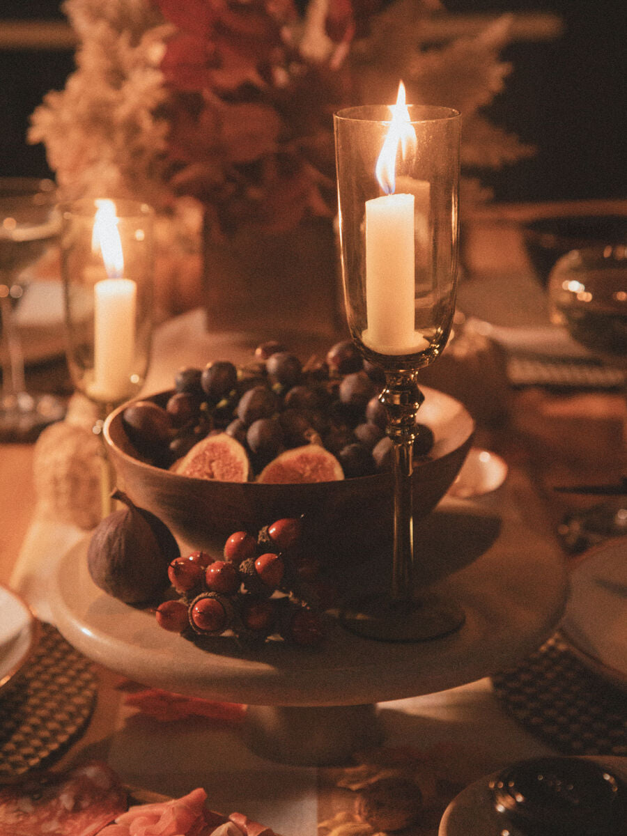 Orsina Cake Stand elegantly displaying fruits and decorative candles on a festive table setting