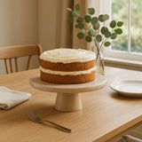 Orsina Cake Stand with a Cream Frosted Layer Cake on a Wooden Table