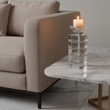 Orsina elegant candle holder on a marble table next to a modern sofa, featuring a lit candle