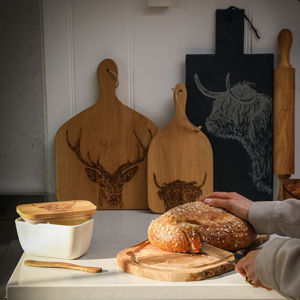 Selbrae House Carving Board with a freshly sliced loaf of bread, surrounded by wooden boards