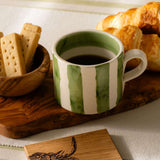 Selbrae House Ceramic Mug with Green Stripes, served with biscuits and croissants on a wooden platter