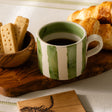 Selbrae House Ceramic Mug with Green Stripes, served with biscuits and croissants on a wooden platter