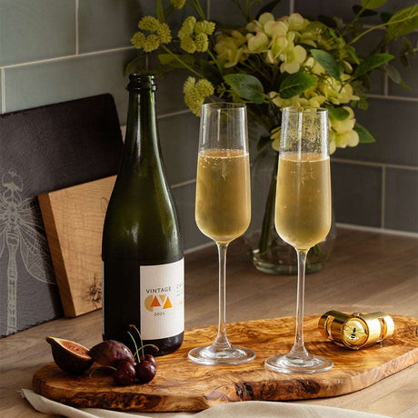 Elegant Selbrae House champagne flutes with sparkling wine and fresh fruit on a wooden serving board