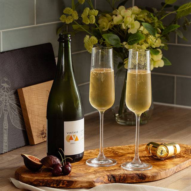 Elegant Selbrae House champagne flutes with sparkling wine and fresh fruit on a wooden serving board