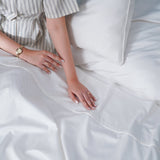 SHEET STORY Flat Sheet displayed on a bed with a stylish striped shirt and elegant bedding accessories