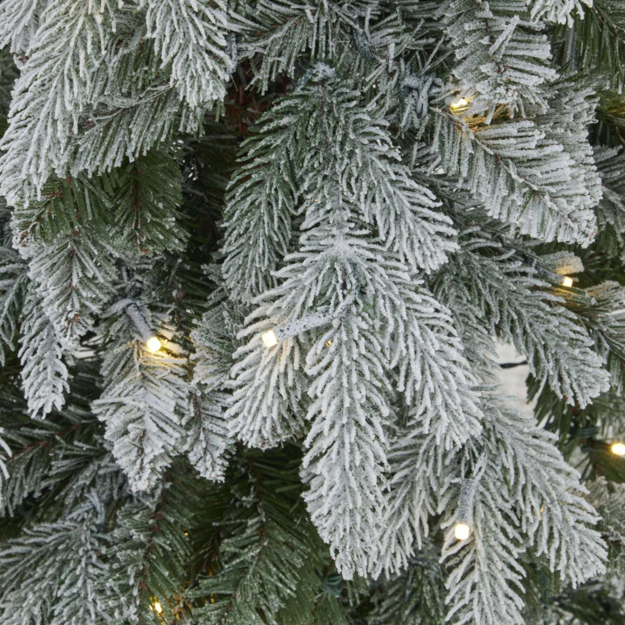 Frosted Christmas Tree branches adorned with warm fairy lights for festive decor