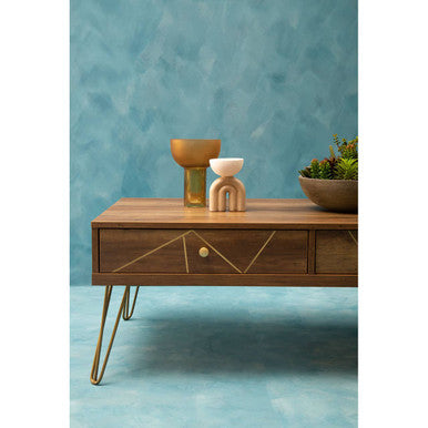 Orsina Coffee Table with geometric design, featuring decorative vases and potted plant on a blue background