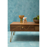 Orsina Coffee Table with geometric design, featuring decorative vases and potted plant on a blue background