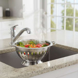 Orsina colander with steam rising, holding fresh vegetables in a modern kitchen sink