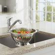 Orsina colander with steam rising, holding fresh vegetables in a modern kitchen sink