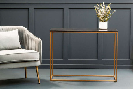 Orsina Console Table with a sleek black surface and gold frame, styled beside a grey armchair