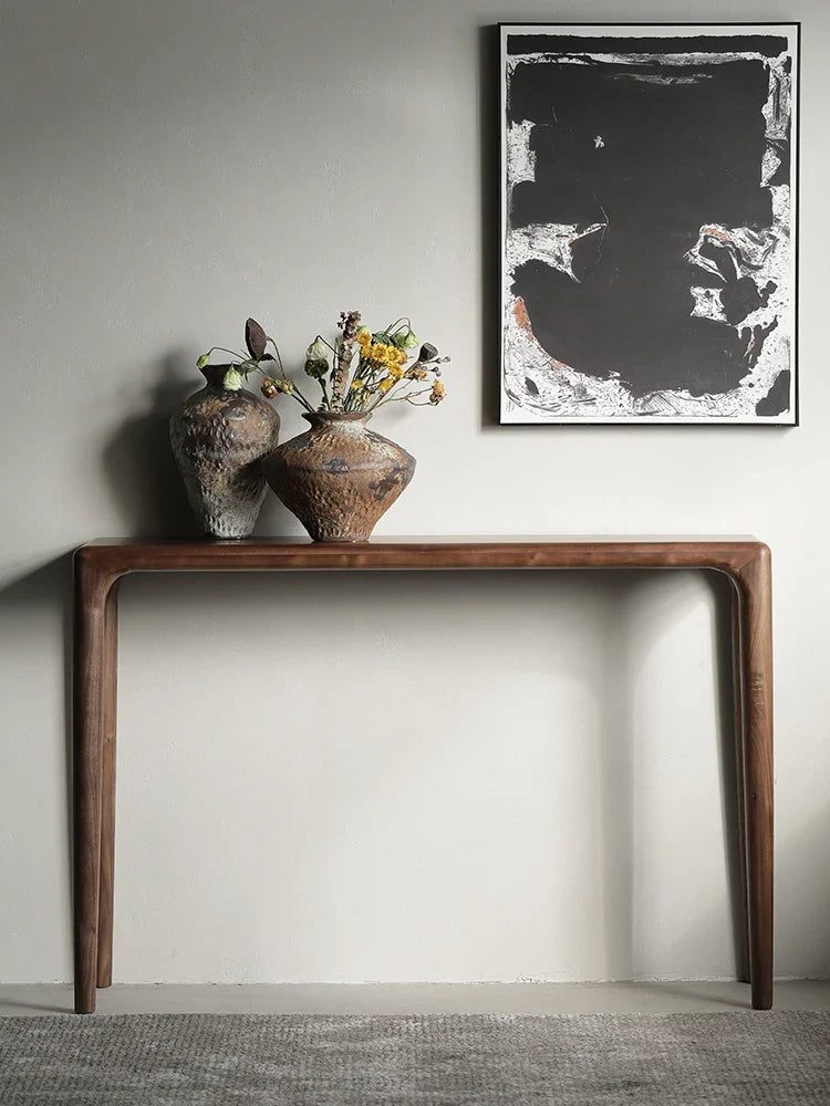 Elegant wooden console table with two decorative vases and artwork on the wall