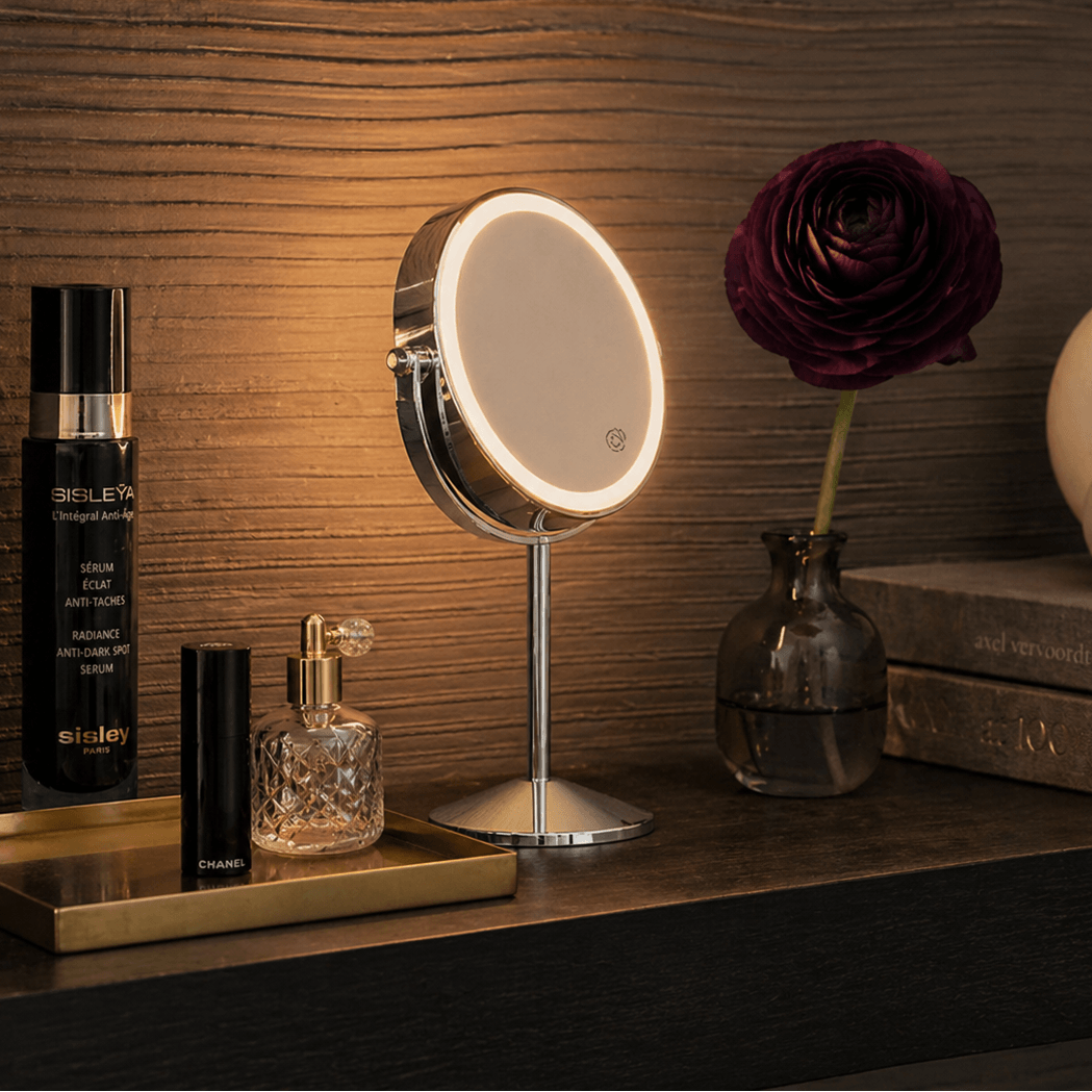 Hollywood cosmetic mirror with adjustable light on a stylish vanity shelf featuring perfumes and a flower