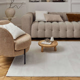 Stylish cream rug placed under a modern beige sofa and armchair in a chic living room setting