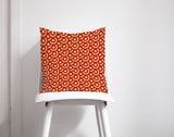 Shadow Bright decorative cushion with a vibrant red and orange geometric pattern on a white chair