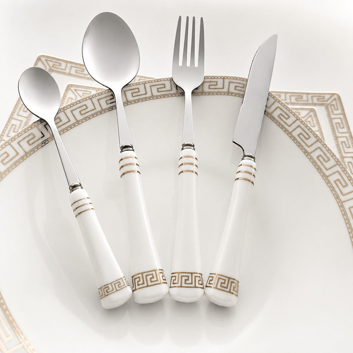 KitchBoom Cutlery Set featuring elegant white handles with gold detailing on a decorative plate