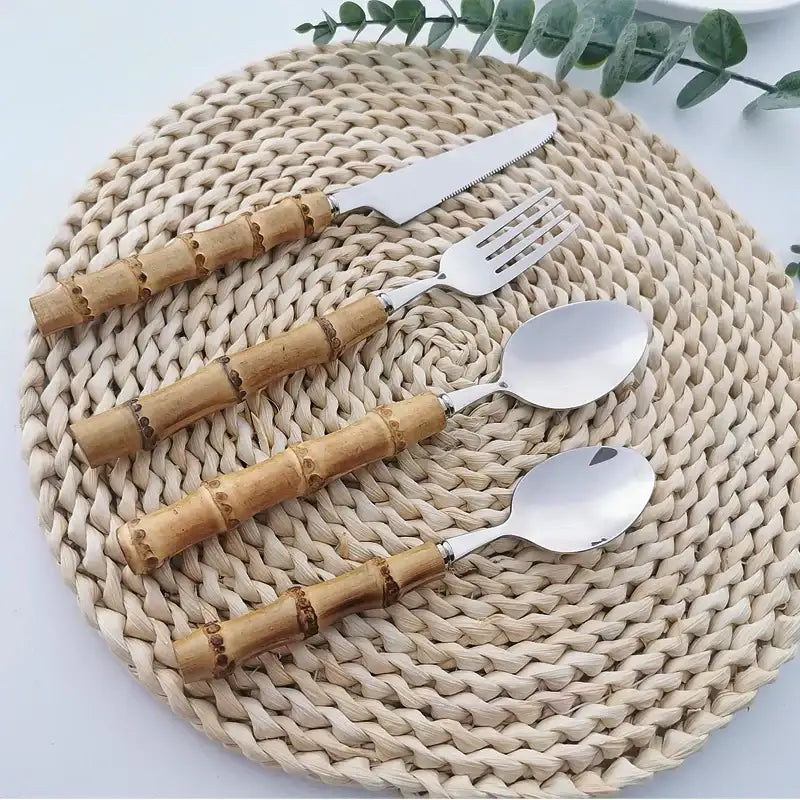 Nisu Home Cutlery Set featuring bamboo handles with knife, fork, and spoons on a woven placemat
