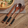 Nisu Home Cutlery Set featuring wooden chopsticks and serving spoon and fork on a table with noodles