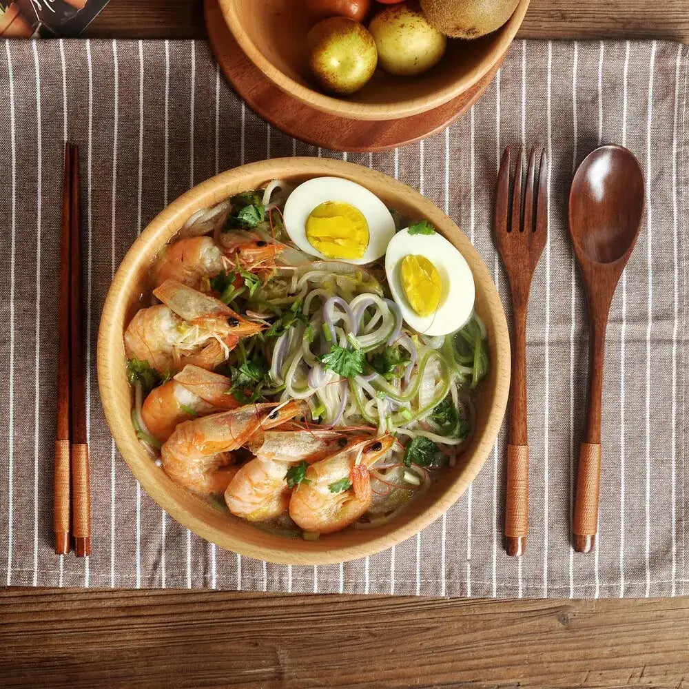 Nisu Home Cutlery Set with wooden spoons and chopsticks next to a bowl of shrimp noodle salad