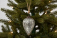 Elegant silver Cone Bauble hanging from a Christmas tree branch adorned with lights