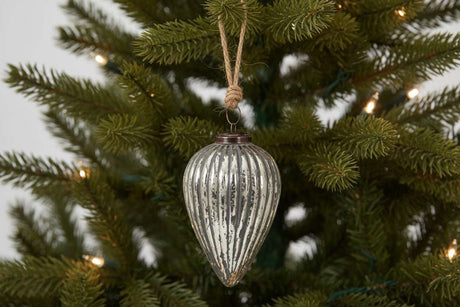 Elegant silver Cone Bauble hanging from a Christmas tree branch adorned with lights