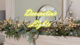 Elegant decorative setting with taper candles surrounded by greenery and fairy lights