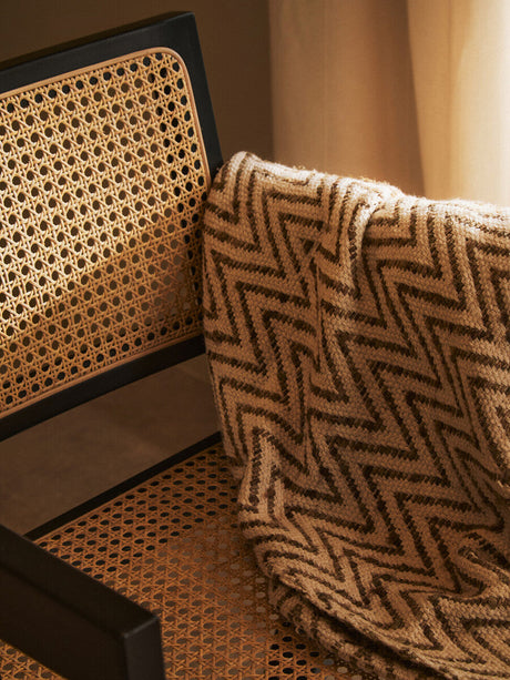 Orsina Dining Chair with Natural Cane and a Soft Blanket Draped Over the Backrest