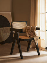 Stylish Orsina dining chair with a minimalist design and cane backrest, draped with a textured blanket