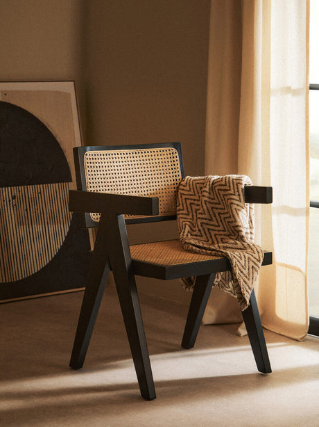 Stylish Orsina dining chair with a minimalist design and cane backrest, draped with a textured blanket