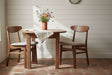 Fishe and Lilly Dining Chair in natural wood finish, paired with a round table and floral decor