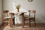 Fishe and Lilly Dining Chair in natural wood finish, paired with a round table and floral decor