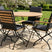 MINT Outdoor Dining Set featuring a round wooden table and four chairs with black fabric and wooden armrests