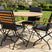 MINT Outdoor Dining Set featuring a round wooden table and four chairs with black fabric and wooden armrests